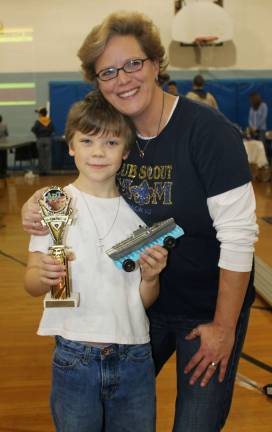 Cub scouts race pine wood derby cars Aidan Ehlberg shows off his winning Battleship car as most creative with his mom, Elise.