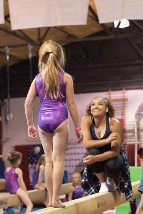 Laurie Hernandez is shown helping a younger gymnast.