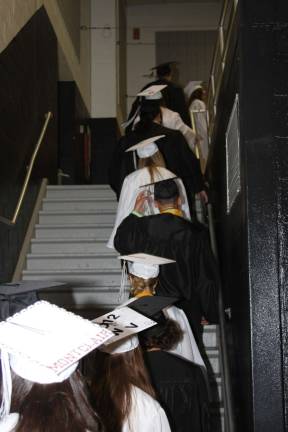 Time to celebrate The senior class heads up the stairs for their graduation ceremony. One student announces on her cap that she's going to Montclair State.
