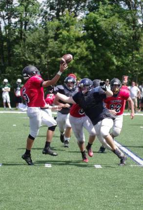 In a scirmmage a Boonton High School quarterback throws while pressured by a Jefferson Township High School defensive lineman on Friday August 19.