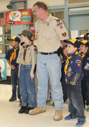 Akela Ciff Graham waits for his Cubmaster neckercheif while sons Fred, a Webelo 2, and Patrick, a wolf scout, stand beside him.