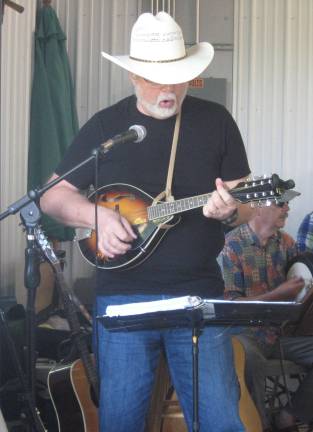 Dulcimer string band opens farmers' market Lew Schafer strums the mandolin and sings a touching folk ballad.