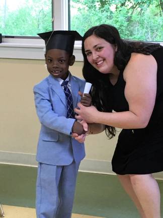 Little Sprouts Early Learning Center preschool graduate Josh Gaspard receives his diploma from teacher Leann Eaton.