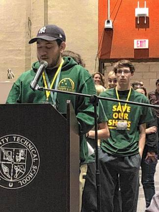 Many people wear T-shirts saying ‘Save our shops’ at the school board meeting.