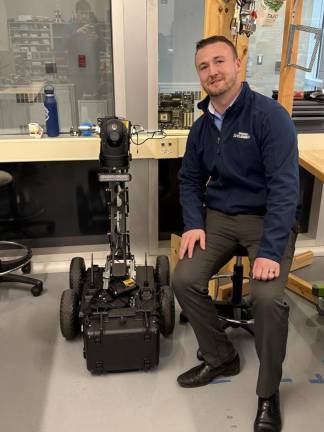 From classroom to career <b>Cory Homer, SCCC’s interim president, poses with the robot that students made for the Newton Police Department. </b>