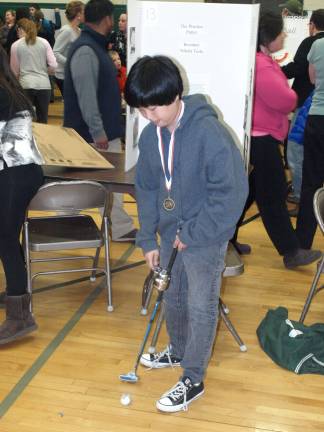 Students get thinking at science fair Sam Paoli demonstrates his practice putter. The ball is attached with a string and can be reeled back in for the next practice putt.