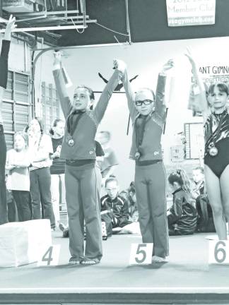 Garden Gators post successful scores in Hackettstown Jadyn DePaolo of Wantage and Ciara Peselli of Newton hold hands as they receive their all-around medals.