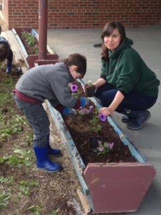 Sullivan and Ashley Sheldon of Hardyston Township plant flowers in a flower box at the Littell Community Center as part of a give back project.