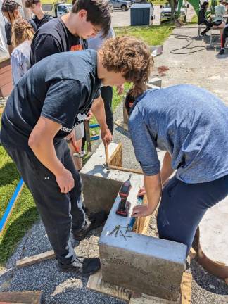 WV3 Industrial arts students remove the wooden molds from the poured concrete forms.