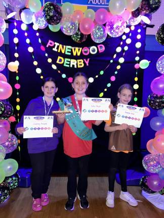 From left, Wallkill Valley Girl Scouts Courtney Mogavero, Sofia Meyer and Anneliese Solar placed third, first and second, respectively, in their service unit’s Glow-in-the-Dark Pinewood Derby, which was a fundraiser for Franklin Cub Scout Pack 90. Each one competed in her Girl Scout level, and the top three from each level advanced to the championship heat. Other winners were Gabby Tussey for best Girl Scout design and Brooke Centi for best glow-in-the-dark design. (Photo provided)