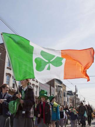 An unidentified girl carries a large Irish flag as she marches along.