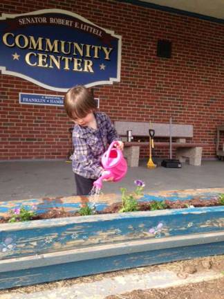 Sheehan Sheldon, 3, of Hardyston Township waters flowers in front of the Littell Community Center in Franklin after a flower planting project as a way to give back to the community center.