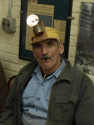 Thomas Hauck, property manager of the Sterling Hill Mining Museum modeling a restored mining hat lamp. The bright acetylene flame is produced by water dripping onto carbide chips inside the body of the lamp. Hauck said the lamp was preferred by older miners as they could light dynamite fuses and their cigarettes with the open flame.