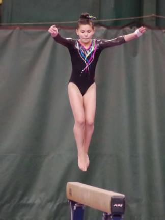 Westy's gymnast Samie Copley in the air above the balance beam.