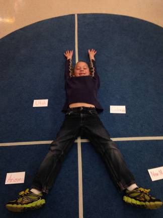 Second-grade student, Noah DeRenzo, demonstrates being in four states at once as he crosses the &#xfe;&#xc4;&#xfa;state boundaries&#xfe;&#xc4;&#xf9; on a four-section carpet labeled with Utah, Colorado, Arizona, and New Mexico.