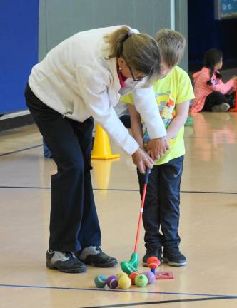 PHOTOS BY VERA OLINSKI Professional golfer Mary Beth Kohberger helps a young boy.