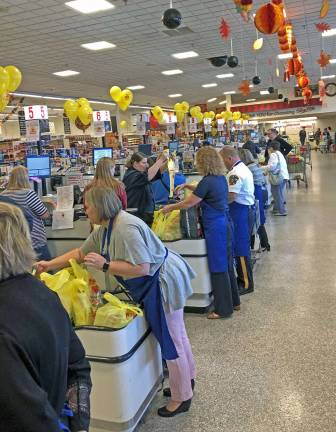 The local dignitaries and special guests bag quickly and carefully while chatting with ShopRite customers.