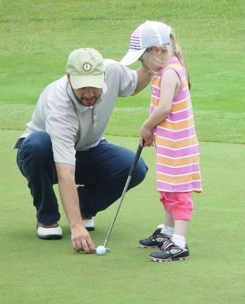 Father Dan Chernowsky helps 5-year-old daughter Hazel line up her putt.