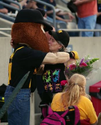 Herbie the Miner gets a hug from a baseball fan he gave a bouquet of flowers to during game.