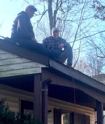 Jeff Jacobus and a member of his crew take a break while working on the roof of a retired custodian at High Point Regional High School.