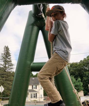 A young boy climbs the rope in the Boot Camp bounce house.