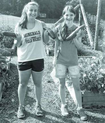 Pass It Along volunteers Adrianna Purcell and Emily Wetzel holding zucchini they just harvested at the Hardyston Charity Garden.