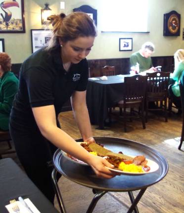 Brianna Ryan of Vernon is shown serving a traditional Irish breakfast that includes (Irish sausages), rashers (Irish bacon), eggs, potatoes, beans, black pudding, white pudding, tomato, and brown bread.