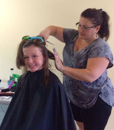 Photos by Laurie Gordon Mackenzie Shea, of Stillwater, gets a haircut at the Project Self-Sufficiency Back-to-School Fair.