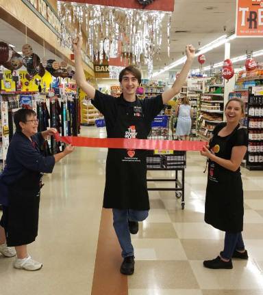 From left, at the Franklin ShopRite, Pam Belott and Kaitlyn Wamback hold the ribbon for John Gieger to help raise awareness for hunger in our communities.