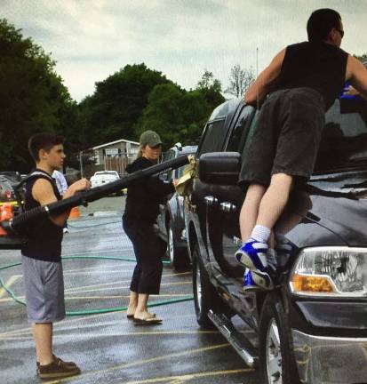 Kids wash and dry the cars.