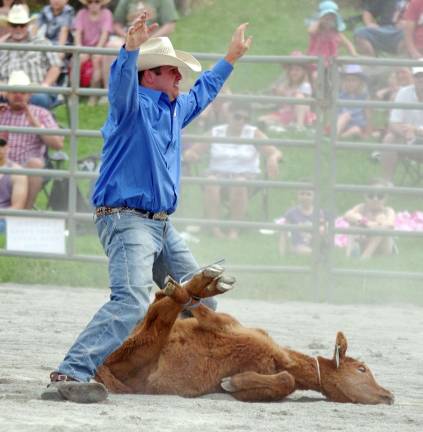 Rodeo competitor Drew Carnes of Hornell, New York raises his arms signalling he is finished binding the calf in the tie down roping contest.