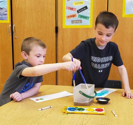 First graders Anthony and Chase working on their feathers
