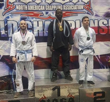 Brian Roth, left, receives a bronze medal for his performance in the men's Blue Belt Gi Brazilian Jiu-Jitsu division.