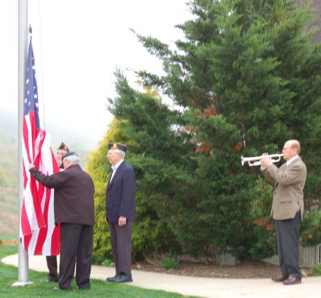 Tom Kieran plays the National Anthem while Jim Cammarano; back towards the camera, Nick Cokinos and Fred Mc Minimim; at rear, prepare to raise the flag.