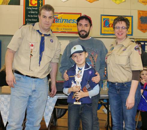 Cub scouts race pine wood derby cars Grand prize winner for fastest car, Justin Hetman, poses with Scout Master Cliff Graham, Leader Barbara Derenzo and his dad, Greg.