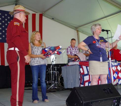 At the right, presenter Barbara Thomas of Wantage speaks about the recipient of a quilt. At the left are Wallkill Valley VFW Memorial Post 8441 of the Veterans of Foreign Wars Commander Jim Davis and the fair's Sponsorship and Events Manager Kristin Vincent.