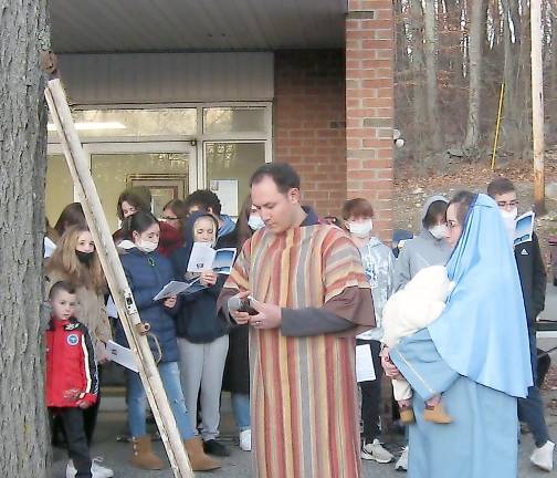 Our Lady of Fatima parishioners tell the story of Christmas Mary and Joseph knock on symbolic doors before finding shelter in a stable (Photo by Janet Redyke)