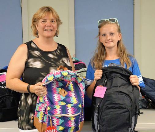 Vernon girl fills backpacks with school supplies for charity From left, Ginnie's House Volunteer and Event Coordinator Maryane Mitchell and Hannah stand before the completed backpacks.