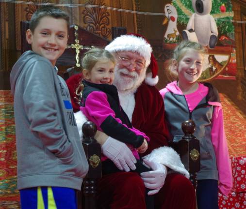 Children visiting with Santa Claus at the indoor Skylands Christmas Village at the stadium Event Center.