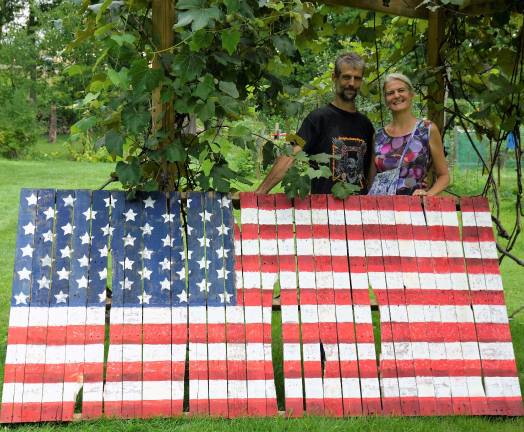 Local resident coordinates local mural project Robert Whitescarver and Stefanie Jasper stand behind Kenny's American flag.