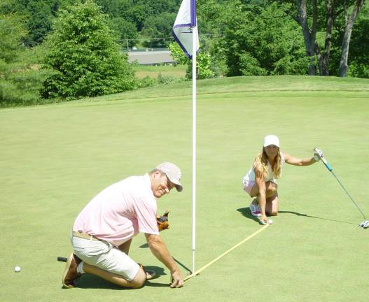 Husband &#x201c;Burner Bob&#x201d; helps wife Dona measure her winning 6&#x2019; 2&#x201d; closest to the tee shot.