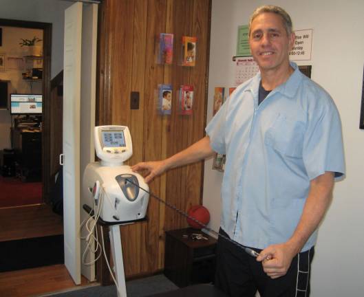 Dr. Peter Karas, celebrating 30 years at the Chiropractic Health Center of Hamburg, sets up the spinal decompression therapy machine.
