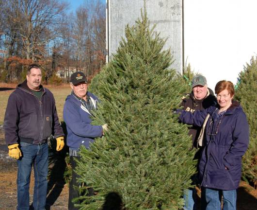 Mr. and Mrs. Mark Fanslau picked this Christmas tree for their home during this holiday season. Jim Squires, left, of the S.A.L. and Michael Murphy, adjutant for Legion Post 423 stand by, ready to deliver the tree to the Fanslau's home.