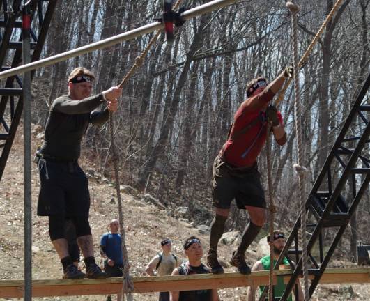 Participants swing over a water and mud-filled obstacle.