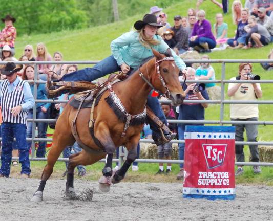 A cowgirl and her horse move fast in the barrel racing event.