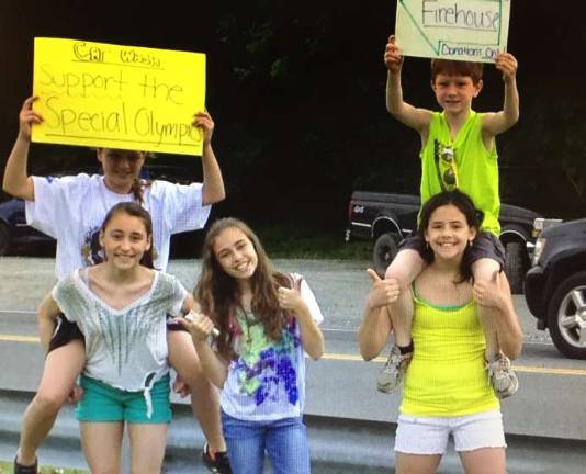 Kids wave cars into the car wash fundraiser for the Special Olympics.