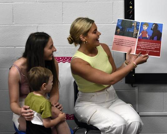 BK2 Seniors Nicole DeFinis, left, and Emily Carey read the book they helped write to preschool student Elliot Joustra.