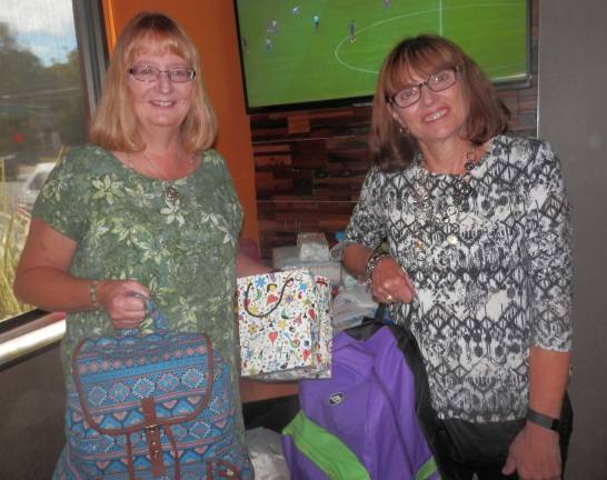 Pictured are Joy Allen and Joan Lucas, members and teachers, assisting in the distribution of supplies.