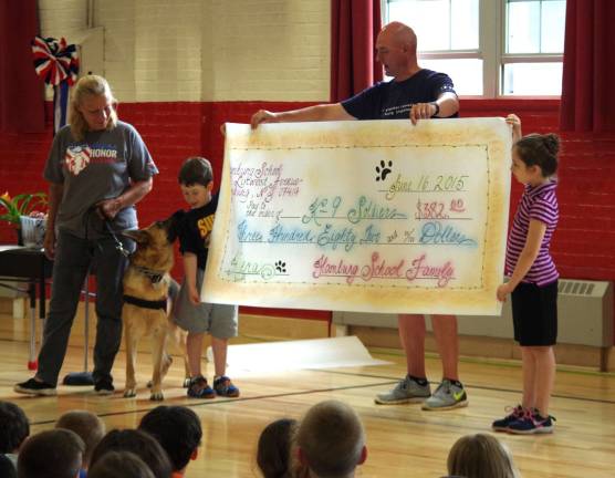 The students and faculty of Hamburg School present a check to K9 Soldiers on Tuesday, June 16. From the left are JT Gabriel of K9 Soldiers, assistance dog Kiera, Samuel Tobachnick, physical education teacher Barry Douglass, and Lily Tobachnick.