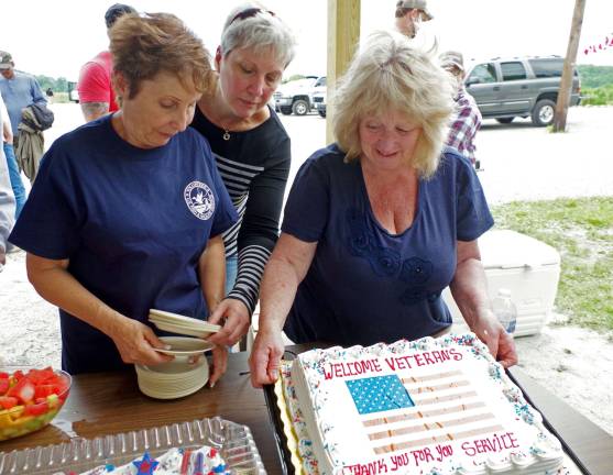 Joyce Schmidt of Hewitt and Lynn Bender of West Milford prepare to serve the two cakes.